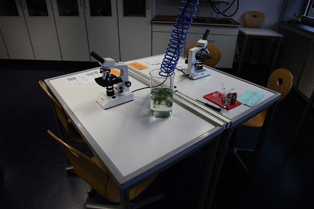 Two microscopes on a table in a school biology room.