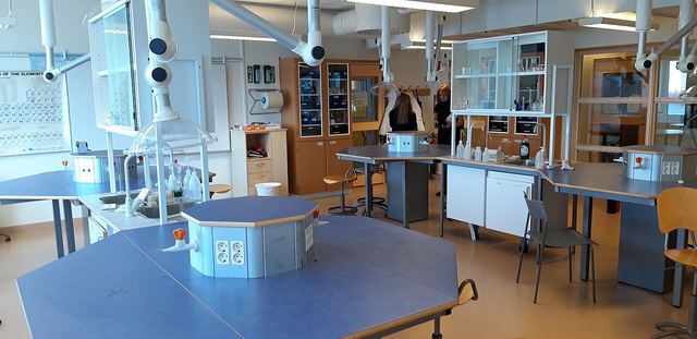A school chemistry laboratory with blue benches, sinks and glassware cabinets.