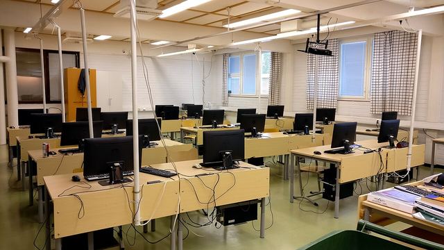 A school computer room with rows of desks and monitors.