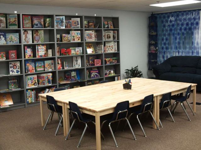 A school library corner with shelves of children’s books and a reading table.