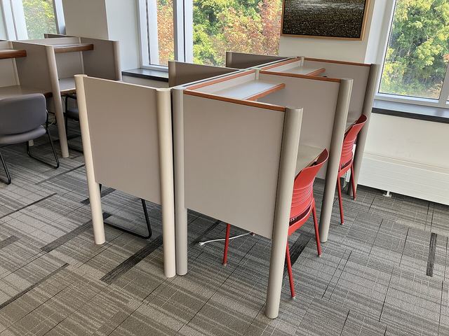 A quiet study area with individual desks beside large windows.