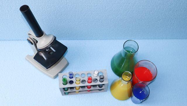 A microscope, a rack of test tubes and flasks of coloured liquid.