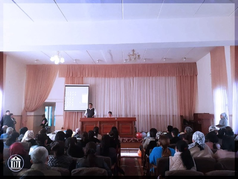 The assembly hall of School No.17 during a meeting, with a stage, a speaker’s table and a projection screen.