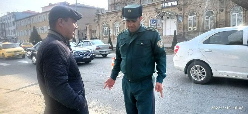 A road-safety officer and a man talking on the street in front of School No.17.